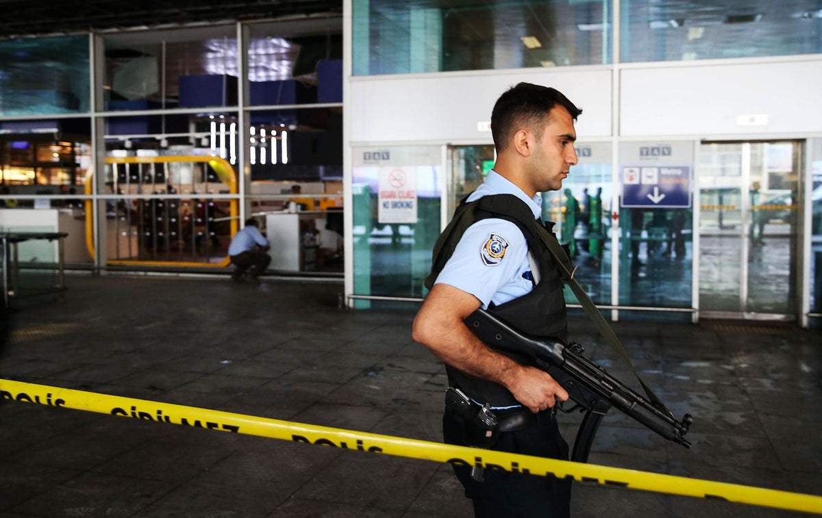 A Turkish police officer stands guard behind police tape at Atatürk Airport's damaged terminal.
