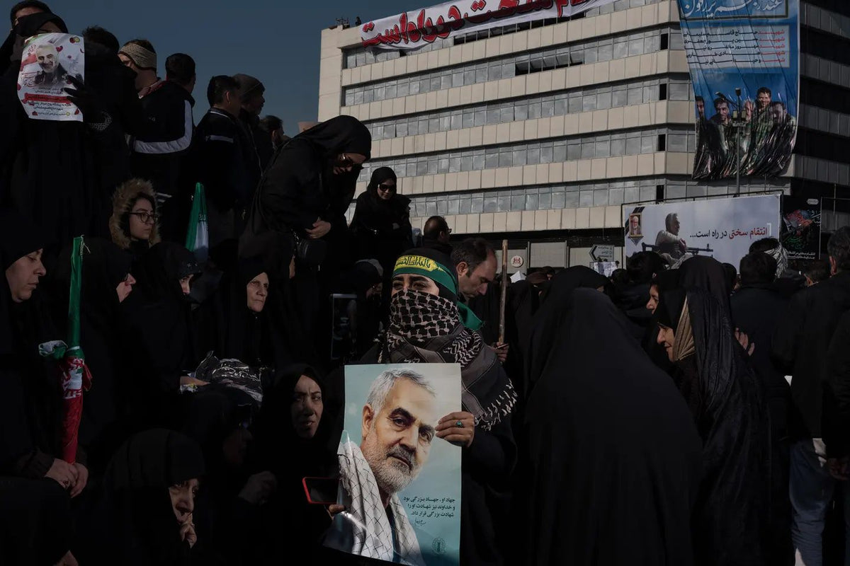 Crowds gather in Tehran to mourn Iranian General Qassem Soleimani, with mourners holding portraits of Soleimani and banners honoring him during a public funeral procession following his death.